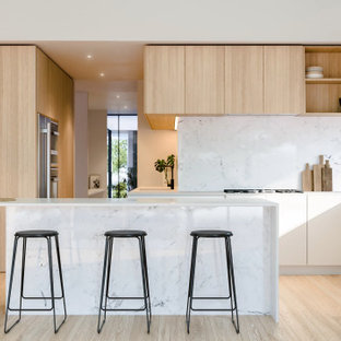Mid-sized contemporary galley open plan kitchen in Perth with an undermount sink, flat-panel cabinets, white cabinets, marble benchtops, white splashback, marble splashback, stainless steel appliances, light hardwood floors, with island, brown floor and white benchtop.