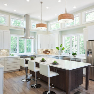 Photo of an expansive transitional u-shaped eat-in kitchen in Atlanta with a farmhouse sink, shaker cabinets, white cabinets, quartz benchtops, beige splashback, glass tile splashback, stainless steel appliances, porcelain floors, with island, beige floor and white benchtop.