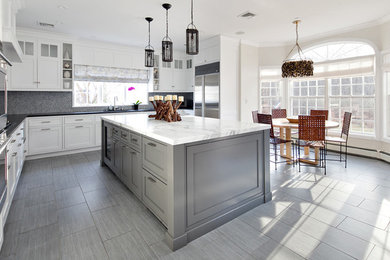 Example of a mid-sized transitional u-shaped porcelain tile and gray floor open concept kitchen design in New York with an undermount sink, recessed-panel cabinets, white cabinets, marble countertops, multicolored backsplash, mosaic tile backsplash, stainless steel appliances and an island