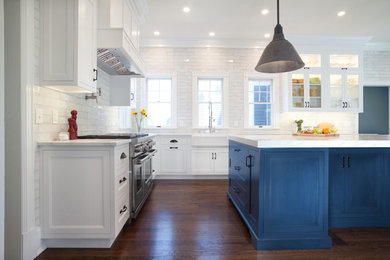 Example of a cottage dark wood floor and brown floor kitchen design in New York with a farmhouse sink, recessed-panel cabinets, blue cabinets, marble countertops, gray backsplash, ceramic backsplash, stainless steel appliances, an island and white countertops