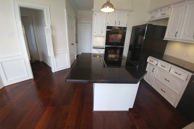 Eat-in kitchen - large traditional u-shaped dark wood floor eat-in kitchen idea in Houston with a double-bowl sink, recessed-panel cabinets, white cabinets, granite countertops, white backsplash, subway tile backsplash, black appliances and an island