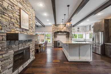 This is an example of an expansive traditional l-shaped open plan kitchen in Houston with a built-in sink, recessed-panel cabinets, dark wood cabinets, granite worktops, grey splashback, cement tile splashback, stainless steel appliances, dark hardwood flooring, an island and brown floors.