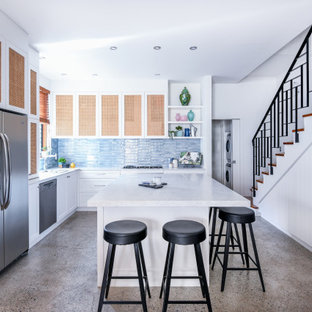 Photo of a large beach style l-shaped open plan kitchen in Sydney with an undermount sink, shaker cabinets, white cabinets, quartzite benchtops, blue splashback, ceramic splashback, stainless steel appliances, concrete floors, with island, grey floor and grey benchtop.