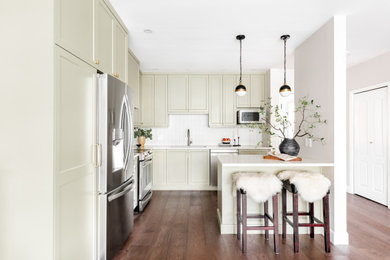 This is an example of a small traditional kitchen in Other with shaker cabinets, green cabinets, white splashback, stainless steel appliances, an island, brown floors and white worktops.