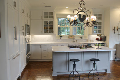 Mid-sized minimalist l-shaped laminate floor and brown floor open concept kitchen photo in Raleigh with a farmhouse sink, shaker cabinets, white cabinets, quartzite countertops, white backsplash, stone slab backsplash, paneled appliances, an island and white countertops