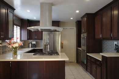 Example of a large trendy u-shaped porcelain tile eat-in kitchen design in San Francisco with an undermount sink, shaker cabinets, brown cabinets, quartz countertops, gray backsplash, glass tile backsplash and stainless steel appliances