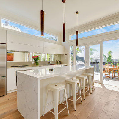 Inspiration for a large contemporary galley brown floor and medium tone wood floor open concept kitchen remodel in Sydney with a drop-in sink, white cabinets, quartz countertops, mirror backsplash, stainless steel appliances, an island, flat-panel cabinets, metallic backsplash and white countertops