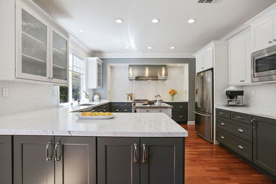 Example of a large transitional u-shaped medium tone wood floor and brown floor enclosed kitchen design in San Francisco with an undermount sink, shaker cabinets, gray cabinets, quartz countertops, white backsplash, subway tile backsplash, stainless steel appliances and an island