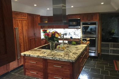 Inspiration for a large transitional u-shaped slate floor kitchen remodel in Miami with an undermount sink, shaker cabinets, medium tone wood cabinets, granite countertops, multicolored backsplash, stone slab backsplash, stainless steel appliances and an island