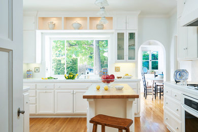 Esempio di una cucina classica chiusa con ante con riquadro incassato, ante bianche, paraspruzzi bianco, elettrodomestici bianchi e pavimento in legno massello medio