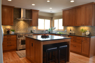 Mid-sized transitional u-shaped light wood floor eat-in kitchen photo in Denver with a single-bowl sink, shaker cabinets, medium tone wood cabinets, granite countertops, green backsplash, ceramic backsplash, stainless steel appliances and an island