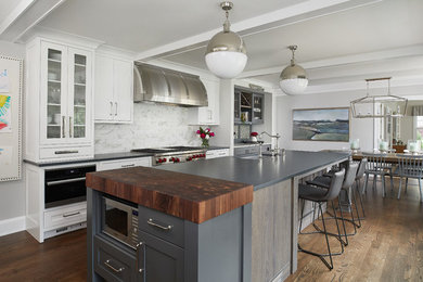 Eat-in kitchen - transitional single-wall dark wood floor eat-in kitchen idea in Grand Rapids with an undermount sink, white cabinets, white backsplash, stainless steel appliances, an island, black countertops and shaker cabinets