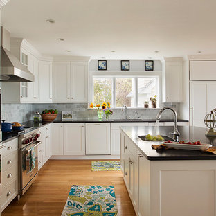 Open concept kitchen - large traditional l-shaped medium tone wood floor open concept kitchen idea in Boston with an undermount sink, shaker cabinets, white cabinets, granite countertops, gray backsplash, stone tile backsplash, stainless steel appliances and an island