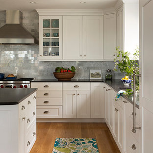 Example of a large transitional l-shaped medium tone wood floor open concept kitchen design in Boston with recessed-panel cabinets, white cabinets, granite countertops, gray backsplash, stone tile backsplash, paneled appliances and an island