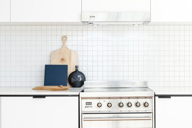 シドニーにある低価格の小さなコンテンポラリースタイルのおしゃれなキッチン (アンダーカウンターシンク、フラットパネル扉のキャビネット、白いキャビネット、クオーツストーンカウンター、白いキッチンパネル、モザイクタイルのキッチンパネル、シルバーの調理設備、無垢フローリング、アイランドなし、白いキッチンカウンター) の写真
