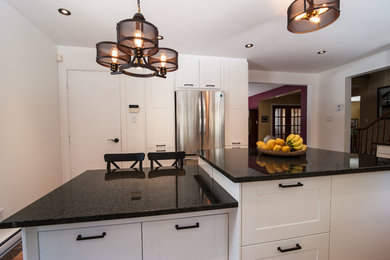Example of a mid-sized transitional galley slate floor eat-in kitchen design in Montreal with a farmhouse sink, shaker cabinets, white cabinets, granite countertops, multicolored backsplash, mosaic tile backsplash, stainless steel appliances and an island