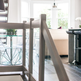Mid-sized contemporary single-wall open plan kitchen in London with an integrated sink, flat-panel cabinets, black cabinets, marble benchtops, white splashback, stone slab splashback, stainless steel appliances, dark hardwood floors and with island.