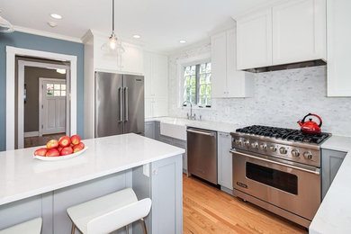Inspiration for a mid-sized cottage u-shaped medium tone wood floor kitchen remodel in DC Metro with a farmhouse sink, gray cabinets, quartz countertops, white backsplash, stainless steel appliances and an island
