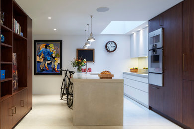 Inspiration for a medium sized contemporary galley kitchen in London with a submerged sink, flat-panel cabinets, dark wood cabinets, integrated appliances, concrete flooring, a breakfast bar, grey floors and beige worktops.