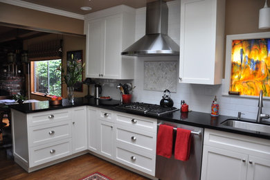 Example of a mid-sized trendy galley medium tone wood floor and brown floor kitchen design in San Francisco with shaker cabinets, white cabinets, stainless steel appliances, no island, a single-bowl sink, white backsplash and subway tile backsplash