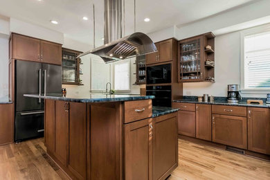 Inspiration for a large transitional u-shaped medium tone wood floor and brown floor eat-in kitchen remodel in Raleigh with a double-bowl sink, shaker cabinets, granite countertops, stainless steel appliances, two islands, dark wood cabinets, beige backsplash and gray countertops