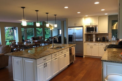 Inspiration for a mid-sized timeless u-shaped dark wood floor kitchen remodel in Seattle with a double-bowl sink, shaker cabinets, white cabinets, granite countertops, beige backsplash, stainless steel appliances and an island