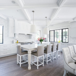 Imagen de cocina comedor en L, tradicional, grande, con armarios con paneles empotrados, puertas de armario blancas, salpicadero blanco, suelo de madera oscura, una isla, fregadero bajoencimera, encimera de cuarcita, electrodomésticos de acero inoxidable y suelo marrón