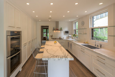 Inspiration for a large classic u-shaped enclosed kitchen in Minneapolis with a submerged sink, shaker cabinets, white cabinets, marble worktops, white splashback, porcelain splashback, stainless steel appliances, dark hardwood flooring and an island.
