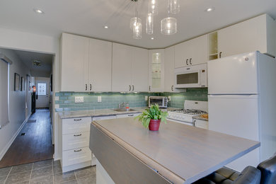 Eat-in kitchen - small transitional l-shaped ceramic tile eat-in kitchen idea in Toronto with a single-bowl sink, shaker cabinets, yellow cabinets, laminate countertops, green backsplash, glass tile backsplash, white appliances and an island