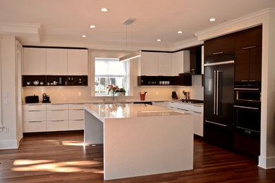 This is an example of a large modern l-shaped open plan kitchen in Other with a submerged sink, flat-panel cabinets, white cabinets, composite countertops, grey splashback, stone slab splashback, stainless steel appliances, dark hardwood flooring, an island, brown floors and grey worktops.