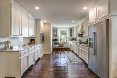 Inspiration for a large country u-shaped dark wood floor and brown floor kitchen remodel in Dallas with an undermount sink, louvered cabinets, white cabinets, white backsplash, subway tile backsplash, stainless steel appliances, an island, quartzite countertops and white countertops