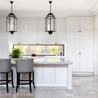 Inspiration for a transitional l-shaped kitchen in Melbourne with raised-panel cabinets, white cabinets, window splashback, stainless steel appliances, with island, grey floor and grey benchtop.