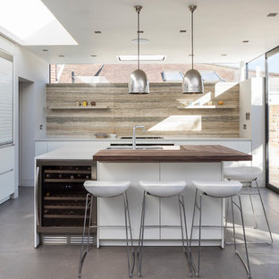 Photo of a large contemporary open plan kitchen in London with an island, a built-in sink, white cabinets, engineered stone countertops, beige splashback, travertine splashback, stainless steel appliances, grey floors, porcelain flooring and flat-panel cabinets.