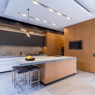 Photo of a large contemporary galley open plan kitchen in Melbourne with an undermount sink, flat-panel cabinets, medium wood cabinets, quartz benchtops, grey splashback, porcelain splashback, black appliances, porcelain floors, with island, grey floor and grey benchtop.
