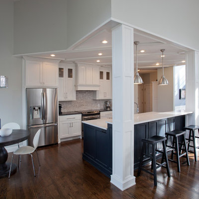 Mid-sized transitional galley dark wood floor and brown floor open concept kitchen photo in St Louis with shaker cabinets, white cabinets, laminate countertops, white backsplash, stainless steel appliances, an island, porcelain backsplash and a farmhouse sink