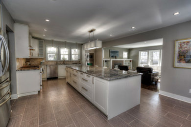 Large transitional l-shaped vinyl floor and gray floor open concept kitchen photo in Milwaukee with a double-bowl sink, shaker cabinets, white cabinets, granite countertops, multicolored backsplash, matchstick tile backsplash, stainless steel appliances and an island