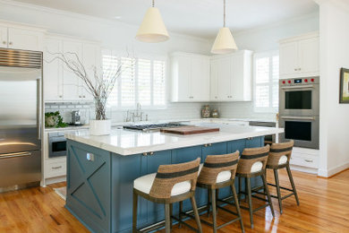 Inspiration for a l-shaped light wood floor and brown floor eat-in kitchen remodel in Charleston with a farmhouse sink, shaker cabinets, blue cabinets, quartzite countertops, white backsplash, stainless steel appliances, an island and gray countertops