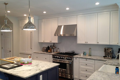 Inspiration for a mid-sized timeless l-shaped eat-in kitchen remodel in New York with recessed-panel cabinets, white cabinets, white backsplash, stainless steel appliances and an island