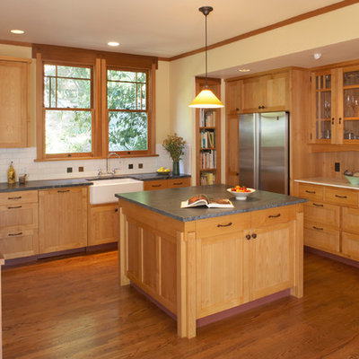 Example of an arts and crafts l-shaped kitchen design in San Francisco with a farmhouse sink, shaker cabinets, medium tone wood cabinets, beige backsplash, subway tile backsplash and stainless steel appliances