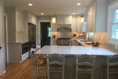 Eat-in kitchen - mid-sized traditional u-shaped medium tone wood floor and brown floor eat-in kitchen idea in Baltimore with white cabinets, quartz countertops, gray backsplash, subway tile backsplash, stainless steel appliances, a peninsula, an undermount sink and recessed-panel cabinets