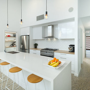 Photo of a contemporary galley kitchen in Other with an undermount sink, flat-panel cabinets, white cabinets, stainless steel appliances, with island, beige floor and white benchtop.