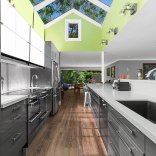 Design ideas for a contemporary galley open plan kitchen in Sydney with an undermount sink, flat-panel cabinets, grey cabinets, stainless steel appliances, dark hardwood floors, with island, brown floor and white benchtop.