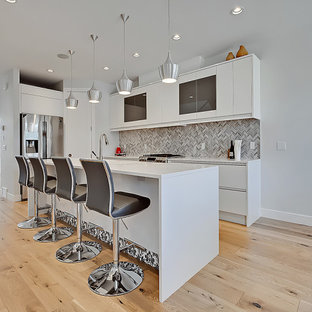 Mid-sized contemporary l-shaped kitchen pantry in Calgary with an undermount sink, flat-panel cabinets, grey cabinets, quartz benchtops, brown splashback, marble splashback, stainless steel appliances, light hardwood floors, with island, multi-coloured floor and white benchtop.