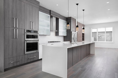 Medium sized contemporary galley open plan kitchen in Calgary with a double-bowl sink, flat-panel cabinets, dark wood cabinets, engineered stone countertops, white splashback, cement tile splashback, stainless steel appliances, medium hardwood flooring and an island.