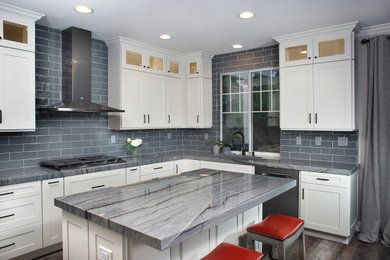 Inspiration for a mid-sized transitional l-shaped medium tone wood floor and brown floor enclosed kitchen remodel in San Diego with an undermount sink, shaker cabinets, white cabinets, granite countertops, gray backsplash, subway tile backsplash, stainless steel appliances, an island and gray countertops
