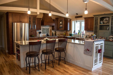 Exempel på ett amerikanskt l-kök, med en rustik diskho, luckor med infälld panel, vita skåp, granitbänkskiva, mellanmörkt trägolv och en köksö