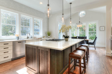 Example of a large transitional medium tone wood floor and brown floor open concept kitchen design in Other with an undermount sink, shaker cabinets, white cabinets, quartz countertops, gray backsplash, matchstick tile backsplash, stainless steel appliances, an island and white countertops