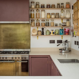 Réalisation d'une petit cuisine américaine design en U avec un évier posé, un placard à porte plane, des portes de placard violettes, un plan de travail en quartz modifié, un électroménager noir et un sol en liège.