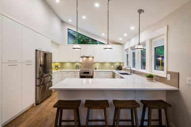 Example of a mid-sized minimalist u-shaped medium tone wood floor and brown floor open concept kitchen design in Other with a double-bowl sink, shaker cabinets, white cabinets, glass tile backsplash, stainless steel appliances, no island and white countertops