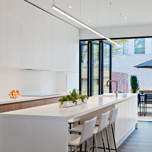 Esempio di una cucina minimal di medie dimensioni con lavello integrato, ante lisce, ante bianche, top in quarzo composito, paraspruzzi bianco, elettrodomestici da incasso, pavimento in legno massello medio e top bianco